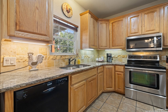 kitchen with light stone countertops, sink, stainless steel appliances, tasteful backsplash, and light tile patterned flooring