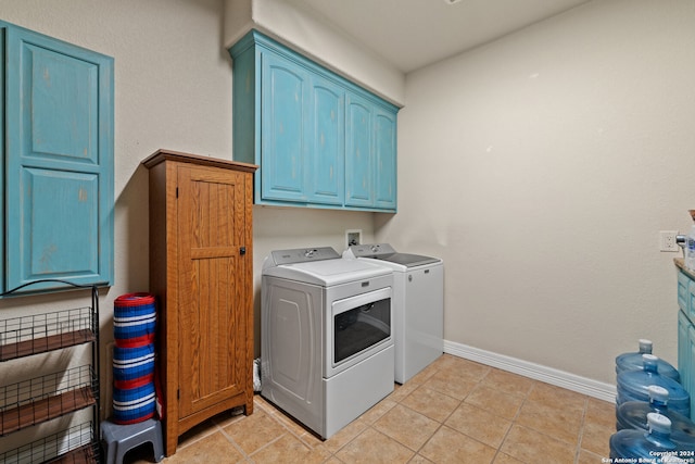 laundry room featuring washing machine and clothes dryer, light tile patterned flooring, and cabinets