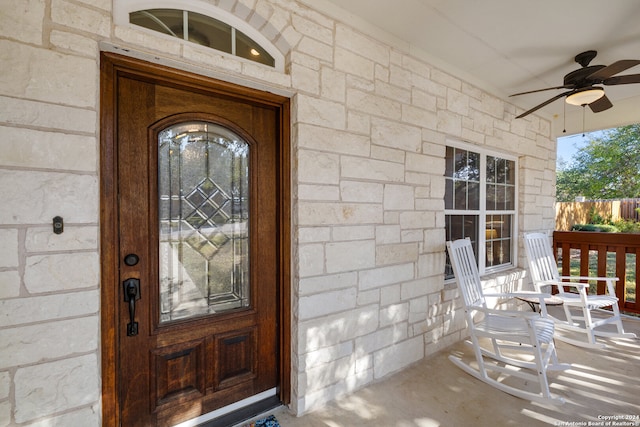 entrance to property with a porch and ceiling fan