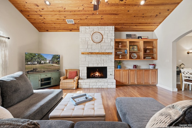 living room featuring a stone fireplace, ceiling fan, light hardwood / wood-style flooring, and wood ceiling