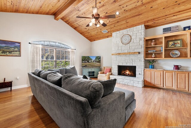 living room featuring a fireplace, light hardwood / wood-style floors, ceiling fan, and beamed ceiling