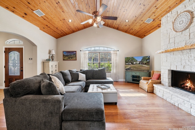 living room featuring a stone fireplace, ceiling fan, wood ceiling, and light wood-type flooring