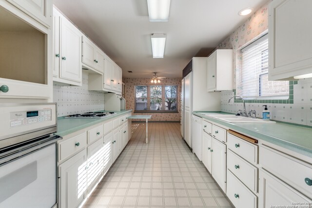 kitchen featuring white cabinetry, plenty of natural light, white appliances, and sink