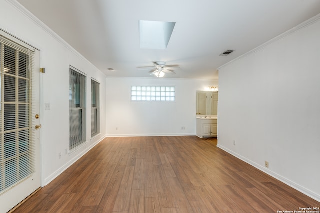 spare room with a skylight, crown molding, ceiling fan, and hardwood / wood-style flooring