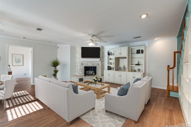 living room with a fireplace, light hardwood / wood-style floors, ceiling fan, and crown molding