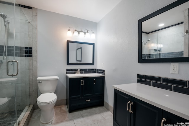 bathroom featuring tile patterned flooring, vanity, toilet, and walk in shower