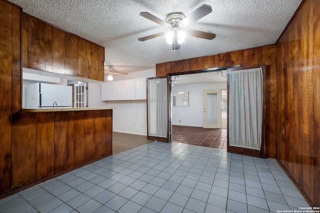 kitchen with wood walls, a textured ceiling, and white refrigerator