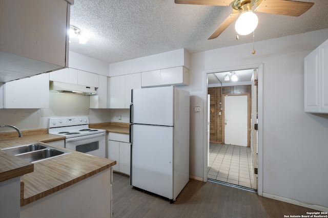 kitchen with white appliances, sink, hardwood / wood-style flooring, white cabinetry, and kitchen peninsula