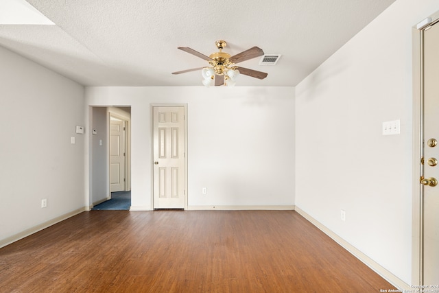 empty room featuring dark hardwood / wood-style floors, ceiling fan, and a textured ceiling