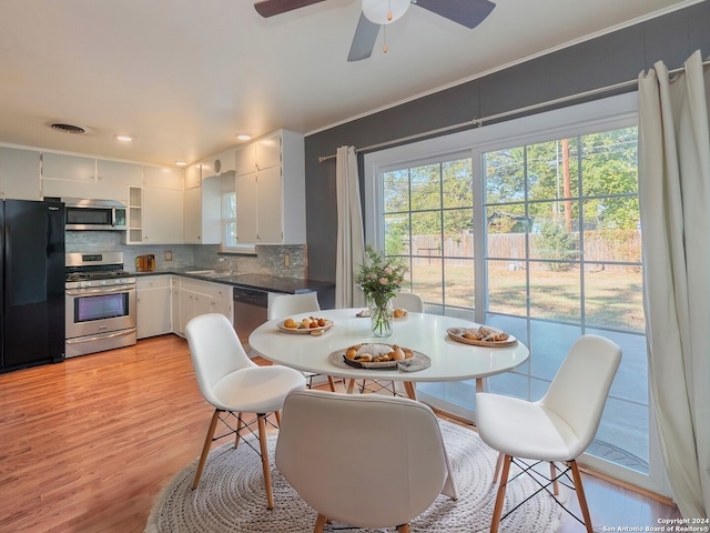 kitchen featuring backsplash, light hardwood / wood-style flooring, ceiling fan, white cabinetry, and stainless steel appliances