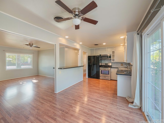 kitchen featuring decorative backsplash, appliances with stainless steel finishes, light wood-type flooring, sink, and white cabinetry