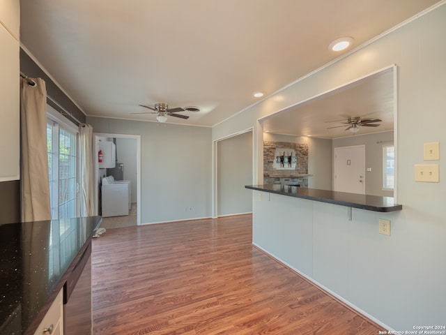 kitchen featuring white cabinets, ceiling fan, a fireplace, wood-type flooring, and washer / clothes dryer