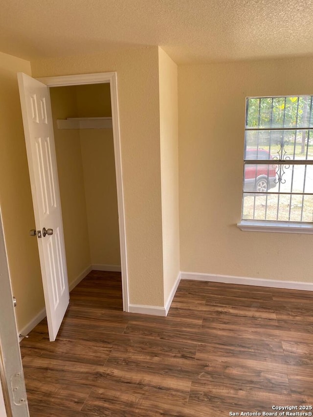 unfurnished bedroom featuring a textured ceiling and dark hardwood / wood-style flooring