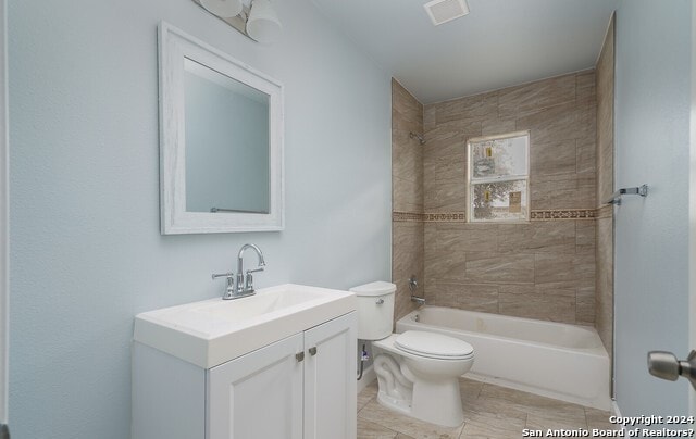 full bathroom with vanity, tile patterned flooring, tiled shower / bath, and toilet