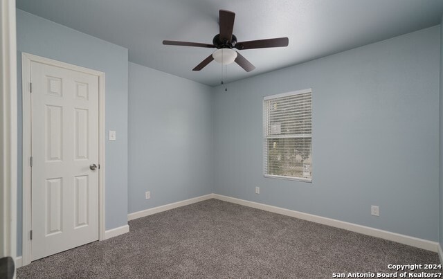 carpeted spare room featuring ceiling fan