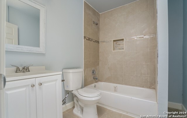 full bathroom featuring tile patterned floors, tiled shower / bath combo, toilet, and vanity