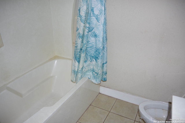 bathroom with tile patterned floors, shower / bath combination with curtain, and toilet