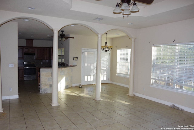 interior space with light tile patterned floors, ceiling fan with notable chandelier, and decorative columns