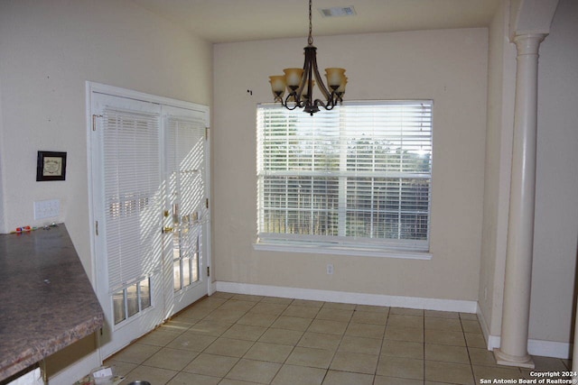 unfurnished dining area featuring decorative columns, tile patterned floors, and a notable chandelier