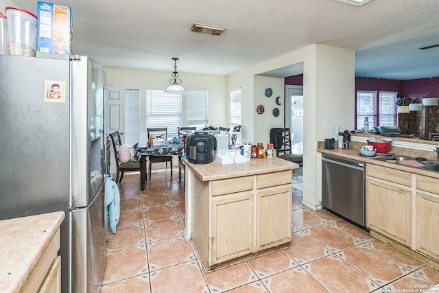 kitchen with pendant lighting, light tile patterned flooring, stainless steel appliances, and light brown cabinets