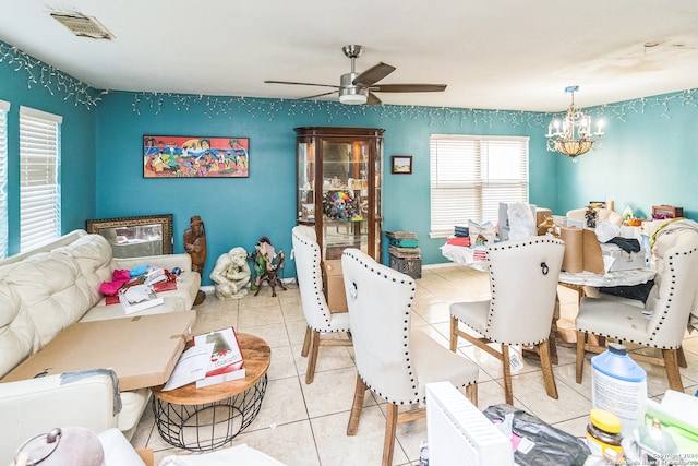 tiled dining room featuring ceiling fan with notable chandelier