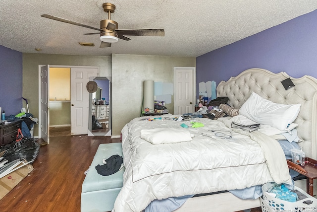 bedroom with ceiling fan, dark wood-type flooring, and a textured ceiling