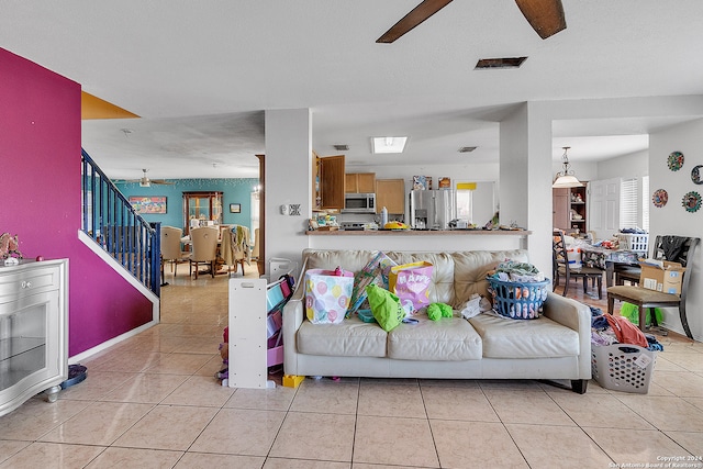 living room with ceiling fan, light tile patterned floors, and a textured ceiling