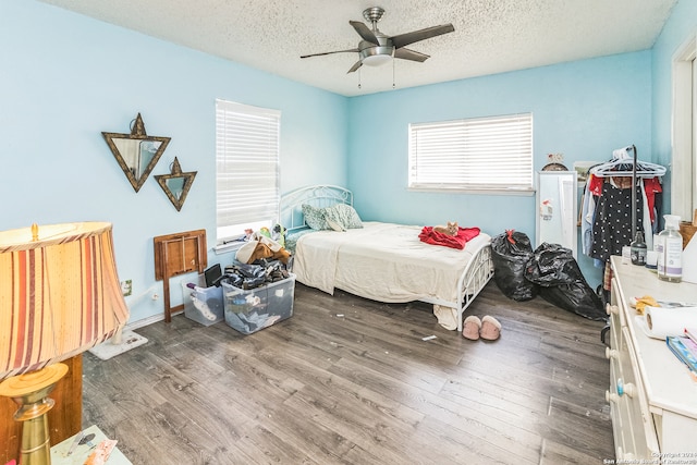 bedroom with a textured ceiling, ceiling fan, and dark wood-type flooring