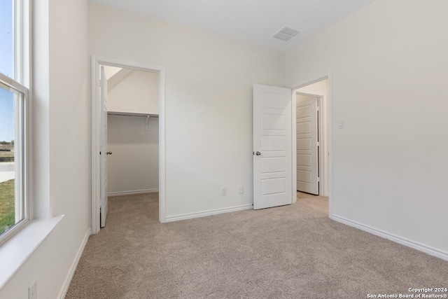 unfurnished bedroom featuring light colored carpet, a spacious closet, and a closet