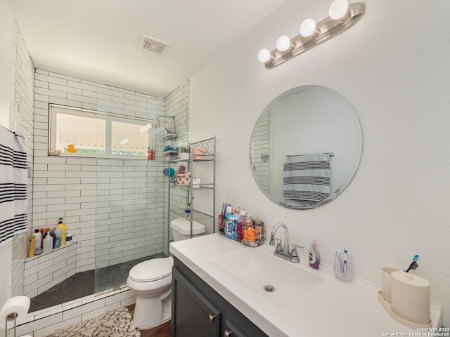 bathroom with a tile shower, vanity, and toilet