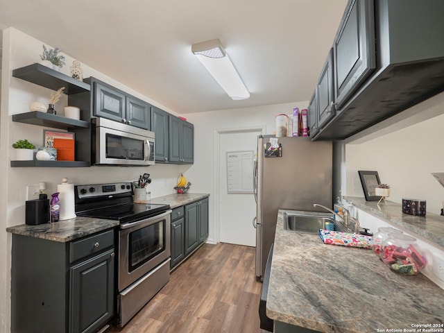 kitchen featuring dark stone countertops, sink, stainless steel appliances, and wood-type flooring