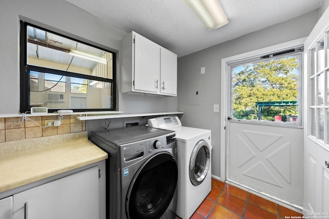 laundry room featuring washing machine and clothes dryer, dark tile patterned floors, cabinets, and a textured ceiling