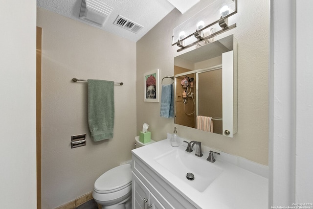 bathroom with a shower with door, vanity, a textured ceiling, and toilet