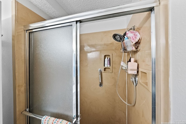 interior details featuring a textured ceiling and walk in shower