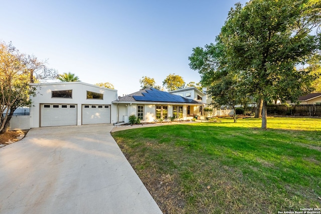 view of front of property with a front yard, solar panels, and a garage