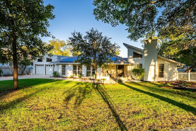 view of front of home with solar panels, a garage, and a front yard