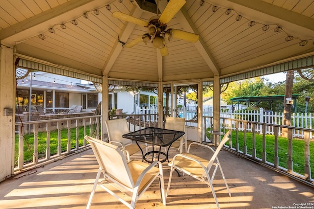 sunroom with ceiling fan, lofted ceiling with beams, and a wealth of natural light