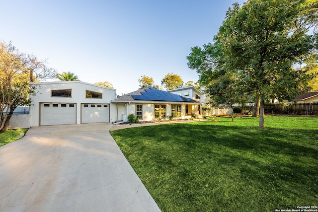 view of front of property with a front yard, solar panels, and a garage