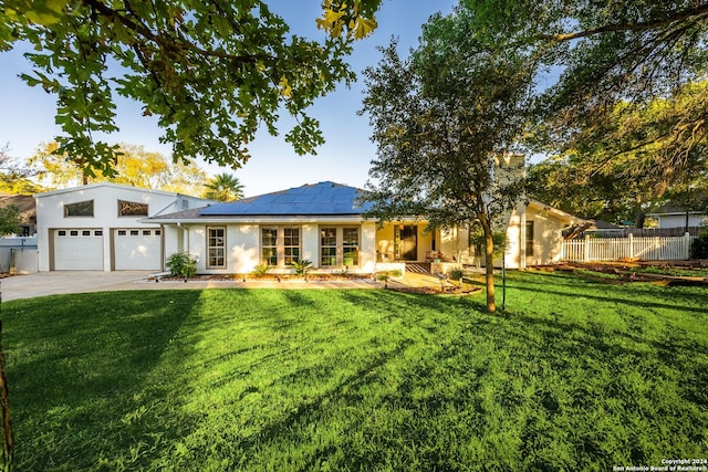 view of front of house with solar panels, a garage, and a front lawn