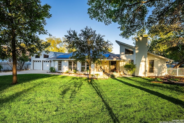 view of front facade featuring a front lawn, a garage, and solar panels