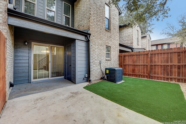 view of exterior entry featuring central air condition unit, a patio area, and a yard