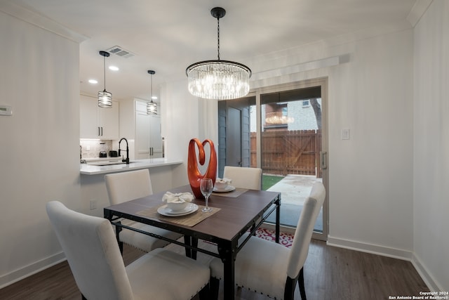 dining space with crown molding, dark hardwood / wood-style floors, and an inviting chandelier