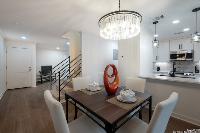 dining area featuring dark hardwood / wood-style flooring, an inviting chandelier, and crown molding