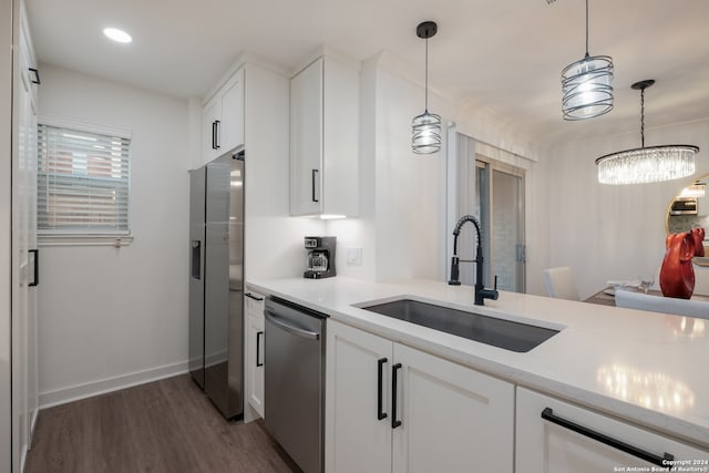 kitchen with stainless steel appliances, white cabinetry, hanging light fixtures, and sink