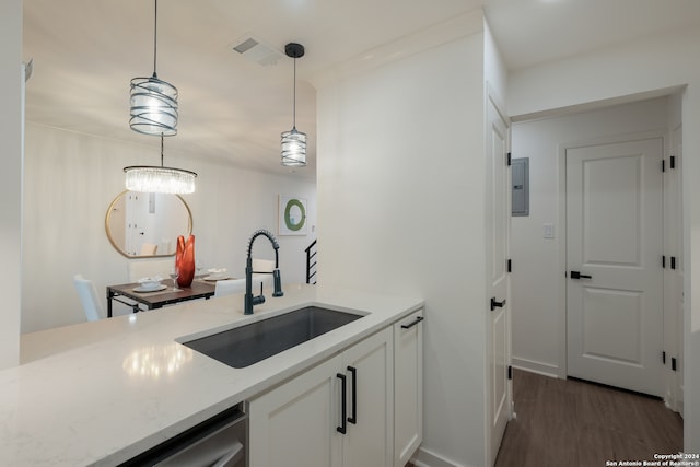 kitchen with light stone countertops, sink, dark wood-type flooring, pendant lighting, and white cabinets