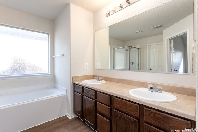 bathroom with hardwood / wood-style floors, vanity, a textured ceiling, and plus walk in shower