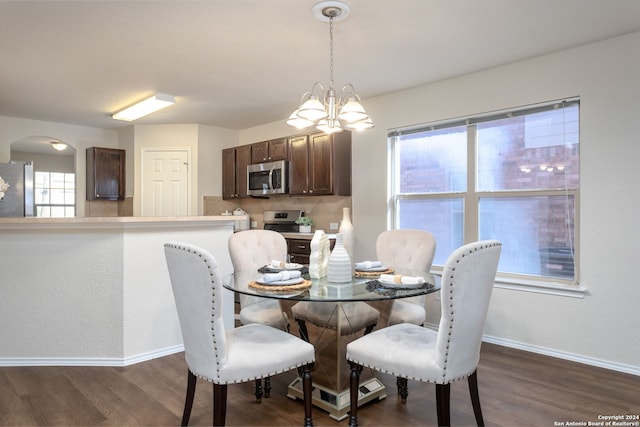 dining room with dark hardwood / wood-style flooring, a wealth of natural light, and an inviting chandelier