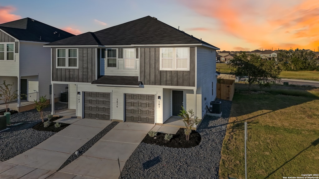 view of front of house featuring a lawn, a garage, and central AC