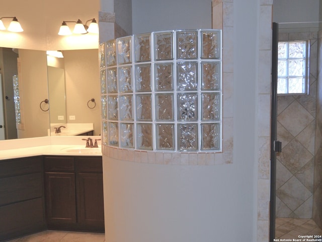 bathroom with tile patterned flooring, vanity, and walk in shower