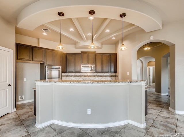 kitchen featuring light stone counters, stainless steel appliances, hanging light fixtures, and tasteful backsplash